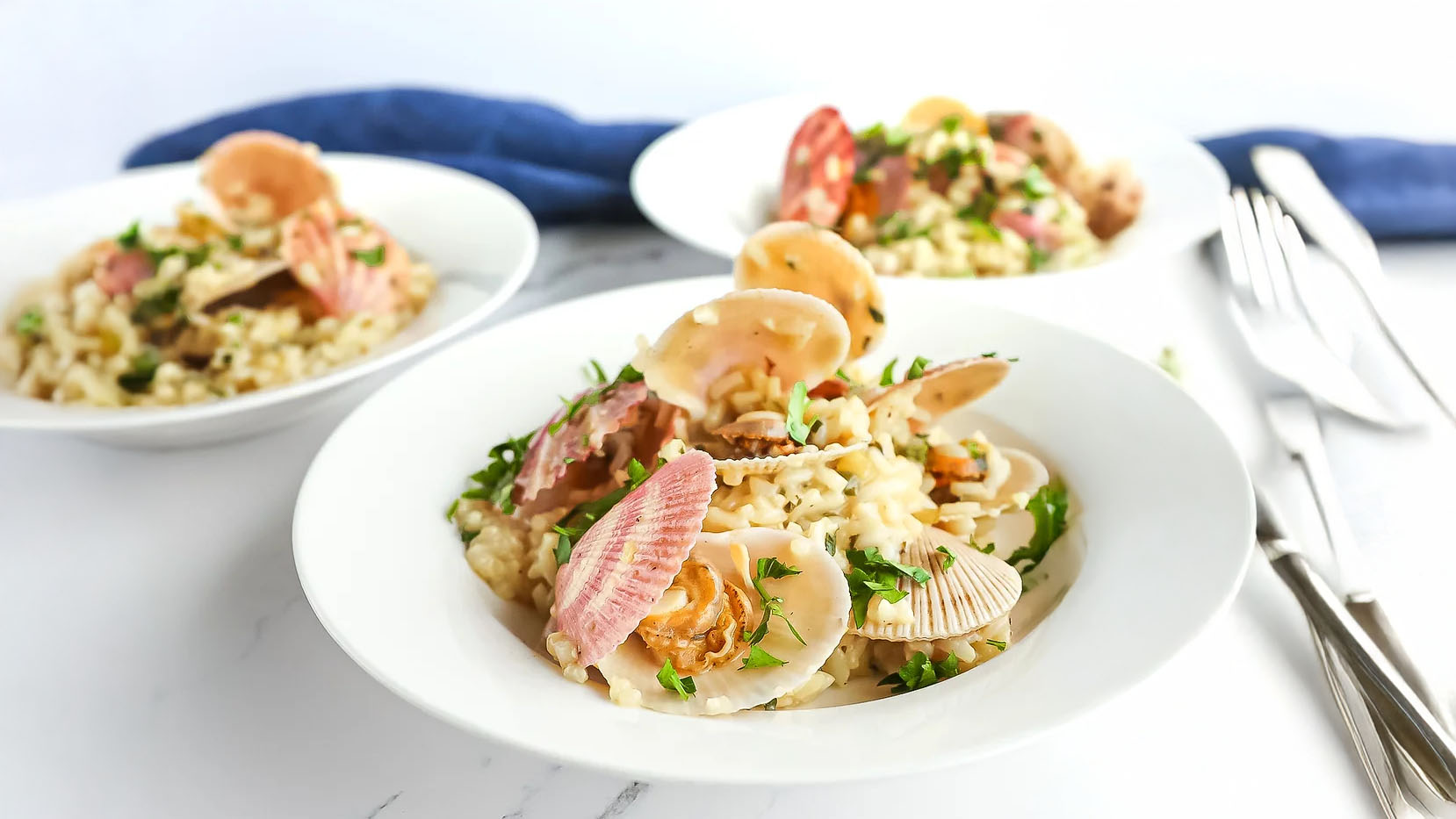 Three plates of risotto topped with scallops